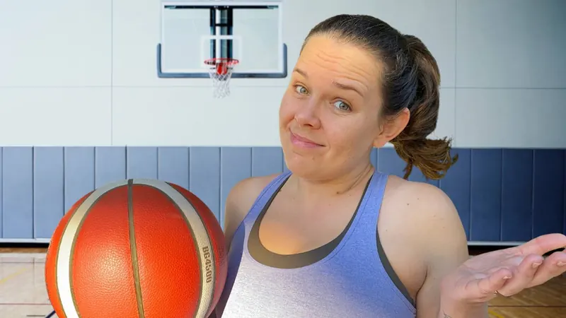 Rach holding a basketball in an indoor court with a hoop behind her